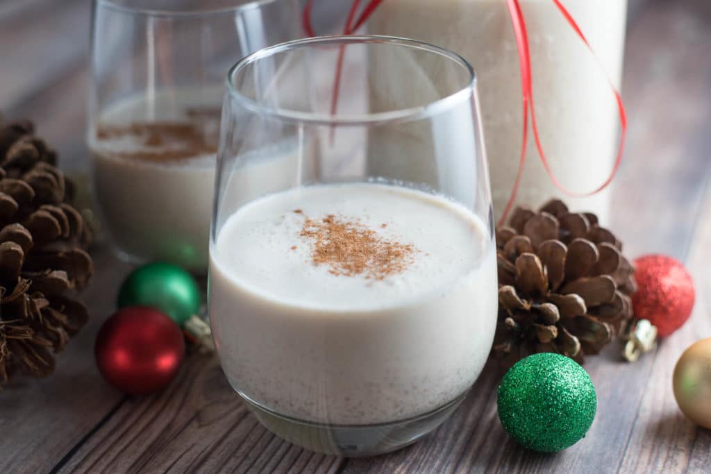 two glasses of coquito surrounded by christmas decorations
