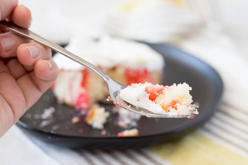 taking a bite out of jello poke cake with a fork
